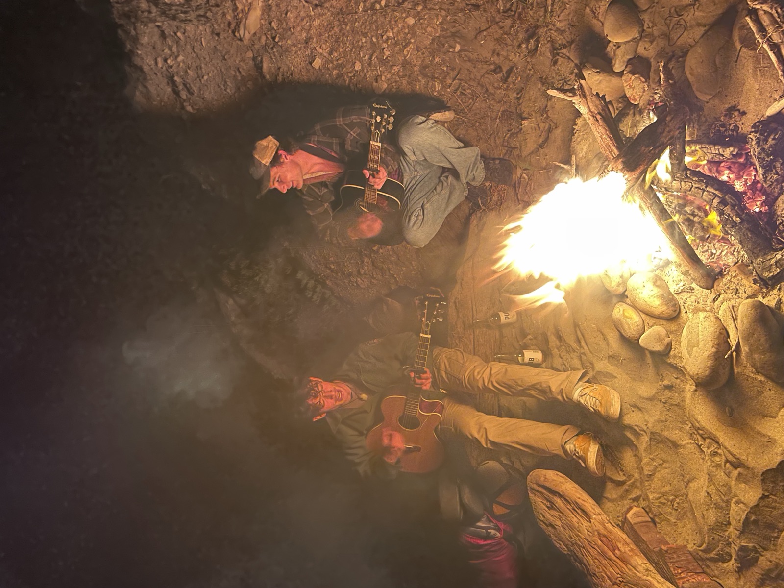 Playing guitar with a friend around a campfire