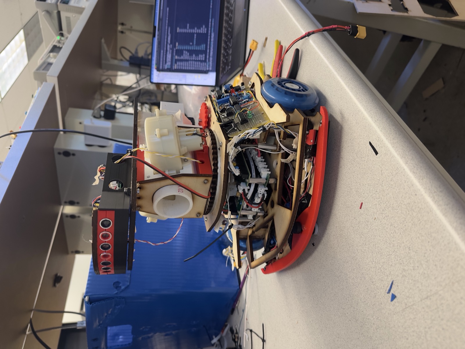 Laser-cut combat robot chassis with stacked electronics on a lab bench