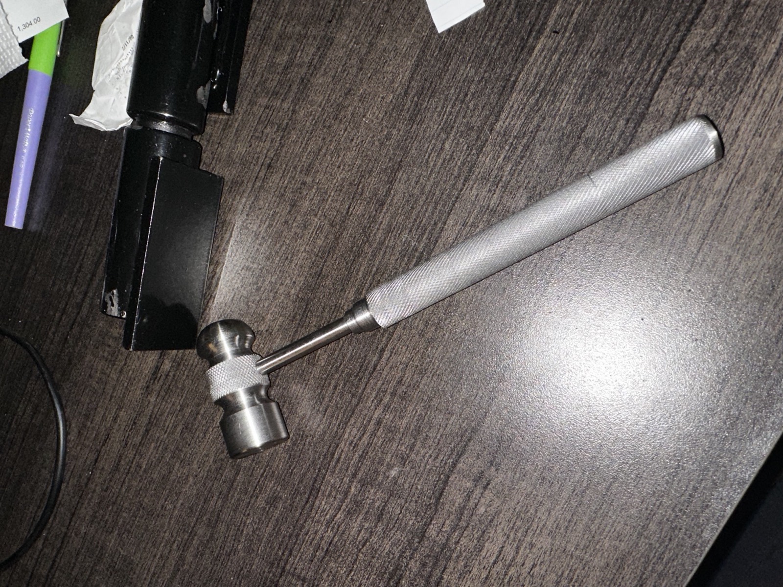 Machined metal hammer with knurled handle on a desk